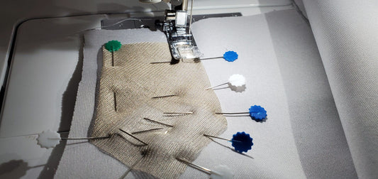 Silver conductive mesh fabric with blue snaps under a sewing machine