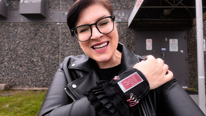 Person wearing a black leather jacket with a visible ePaper jewellery on wrist, standing outdoors.