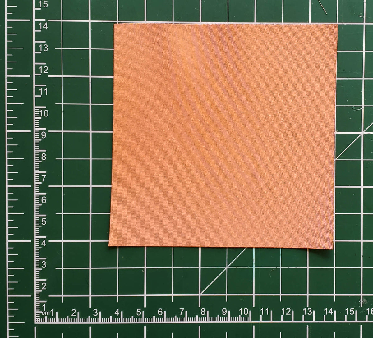 Square of copper conductive fabric on a green cutting mat