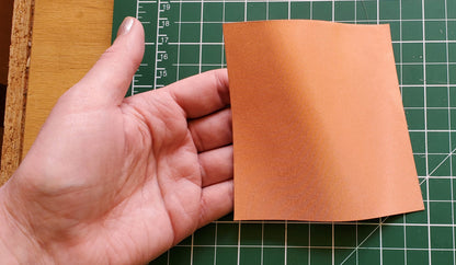 Hand holding a square of copper conductive fabric