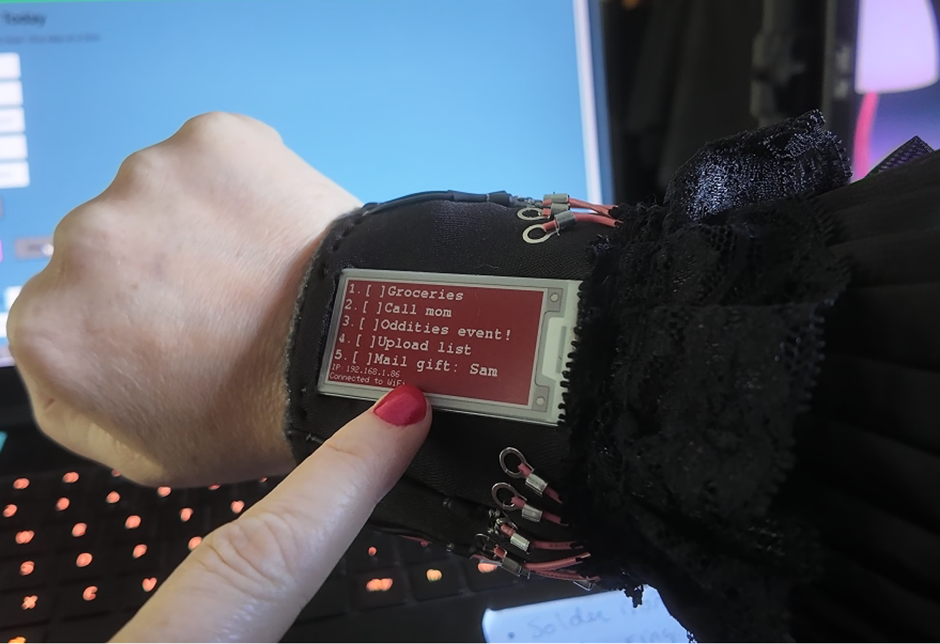 Hand wearing a smartwatch with a computer screen displaying code in the background