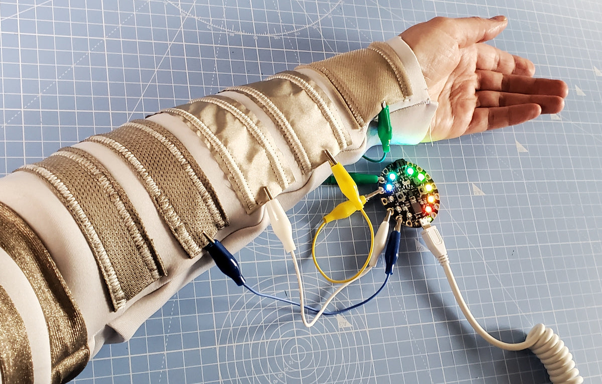 OUIS touch sleeve with conductive fabric strips and a circuit board on an arm