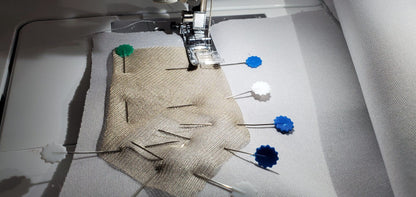 Silver conductive mesh fabric with blue snaps under a sewing machine