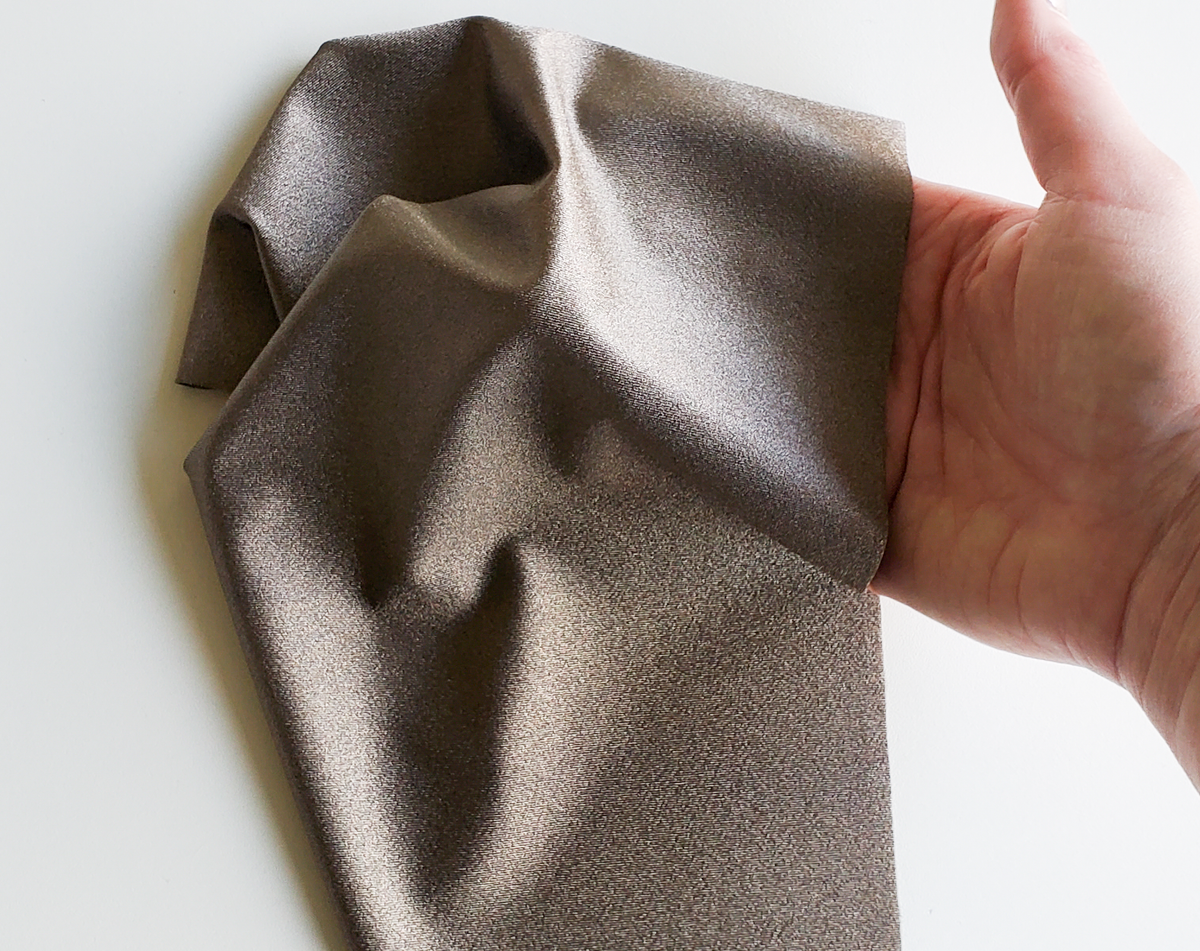 Silver woven stretch conductive fabric held and stretched in hand